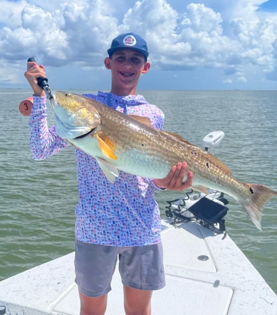 young fisherman holding a large redfish