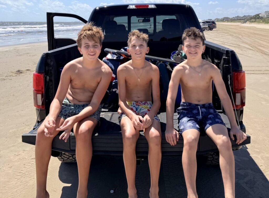 three young boys on the tailgate of a truck